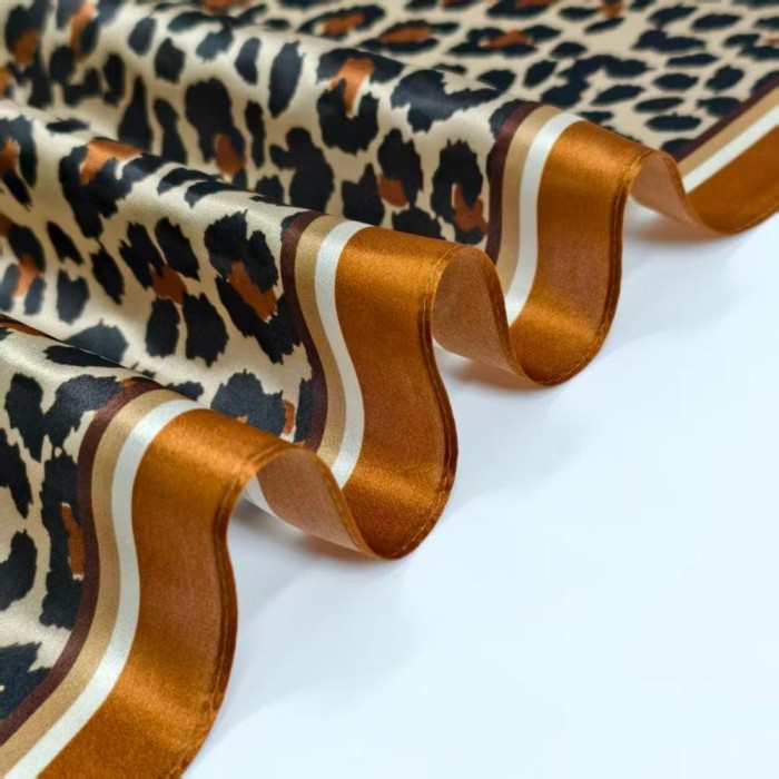 Zbliżenie na jedwabną apaszkę w panterkę z brązowym wykończeniem Silk Avenue